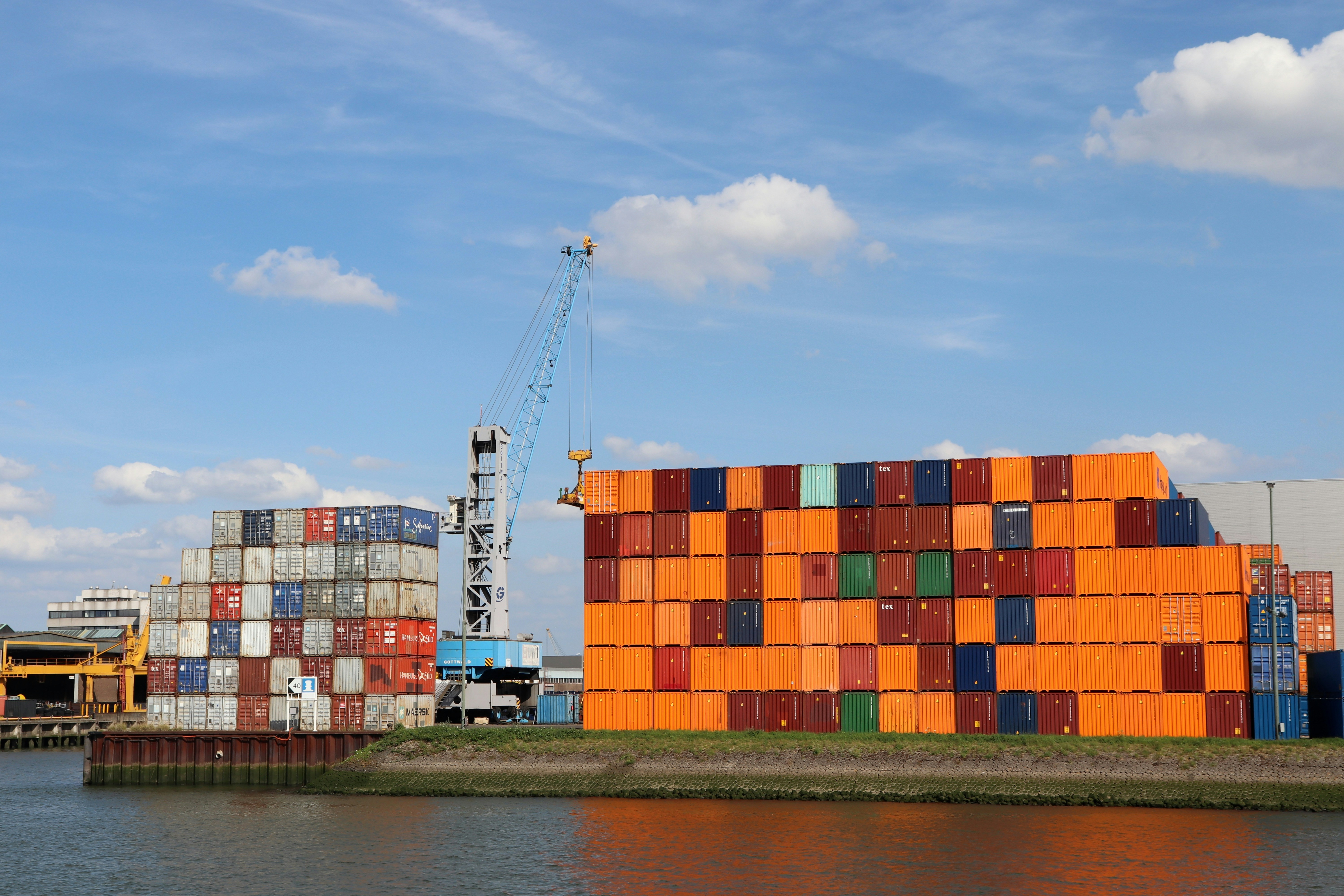 Port of Rotterdam with stacked containers by the water, ready to be transported to the yard, illustrating European logistics and port operations.