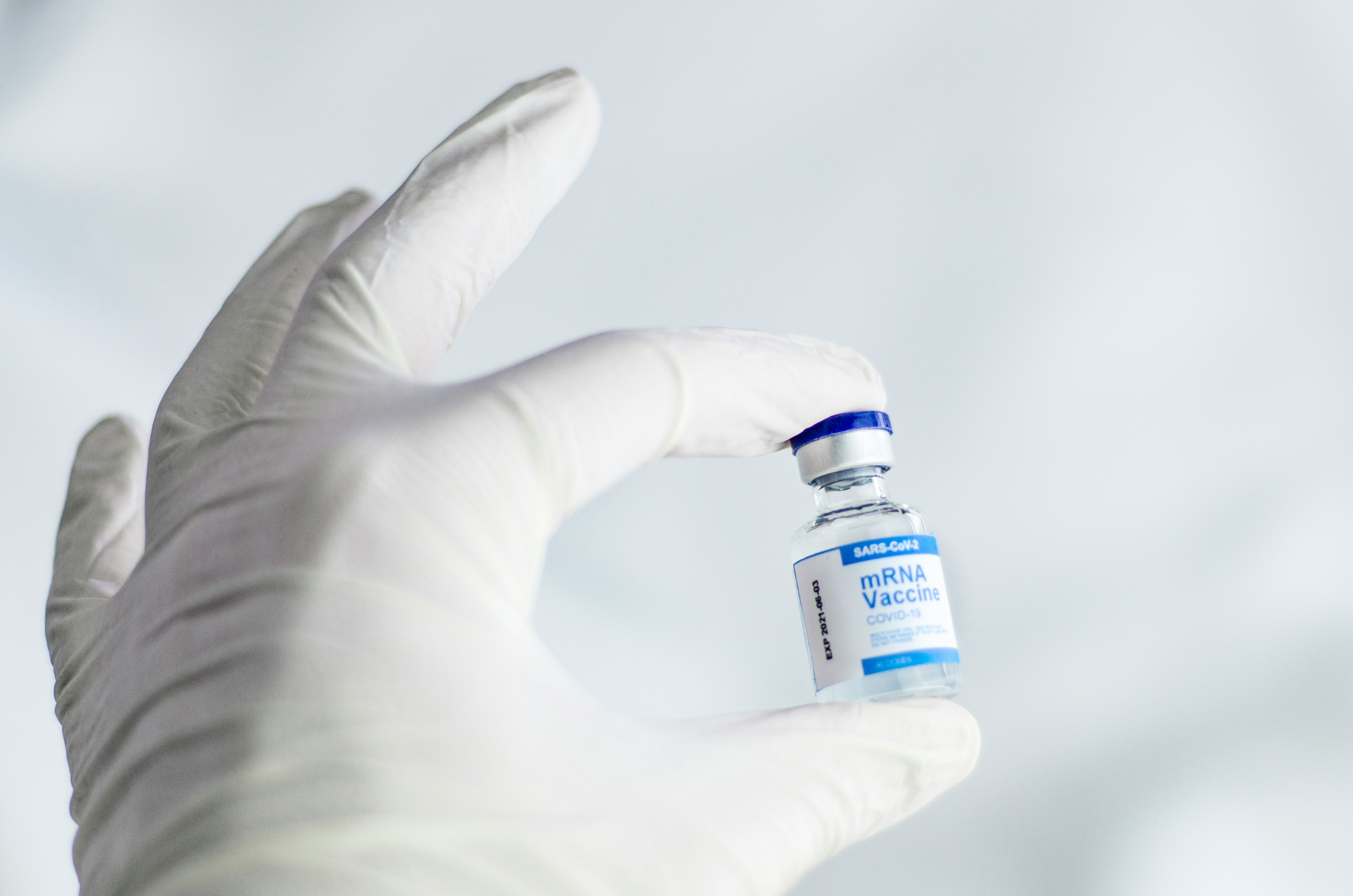 A healthcare professional carefully holding a vial of vaccine in a clinical setting, illustrating the critical importance and sensitivity of pharmaceutical cold chain logistics in ensuring safe and effective delivery of life-saving medicines to patients.