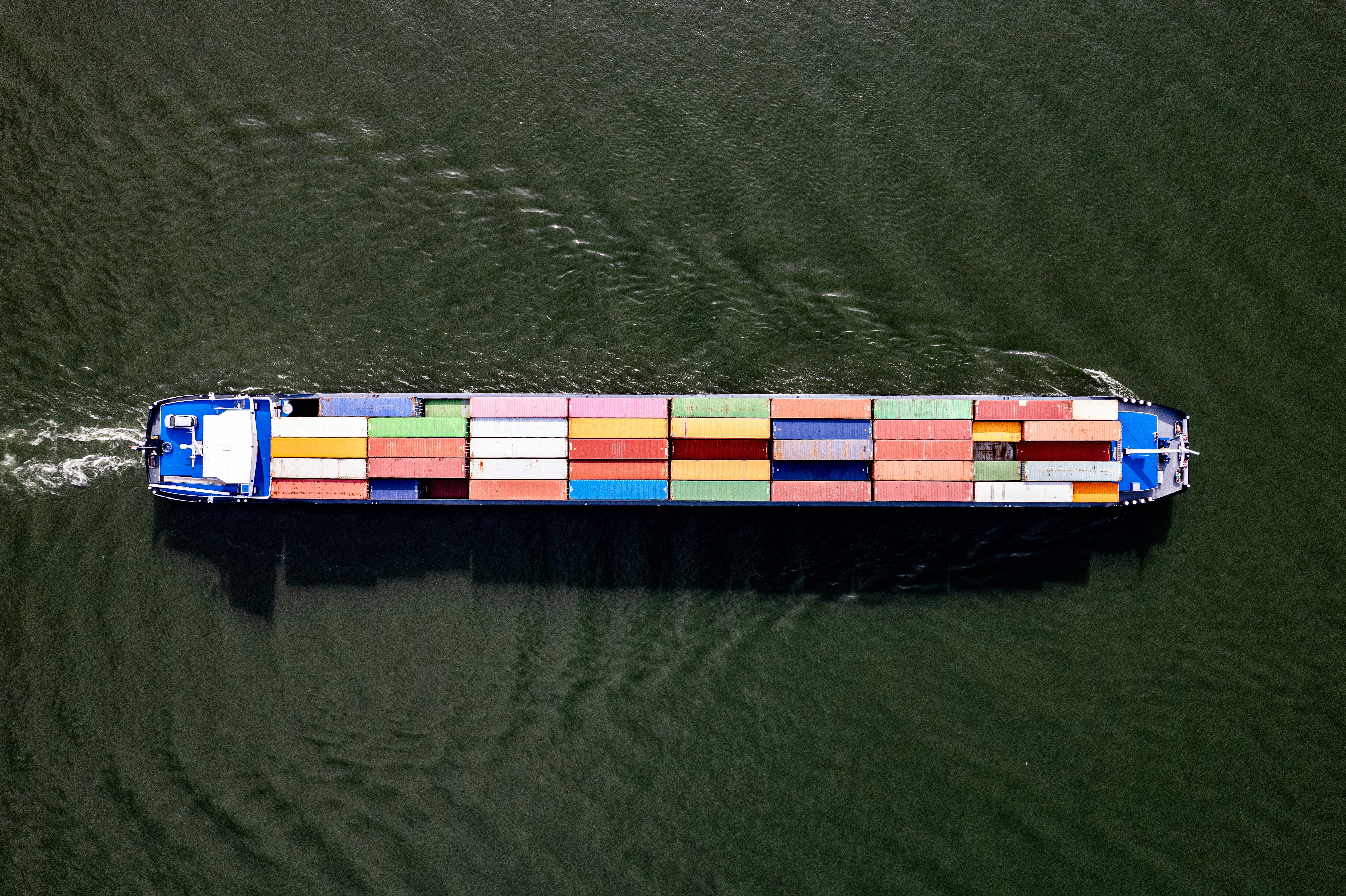 Aerial view of a cargo ship carrying multicolored shipping containers on water.